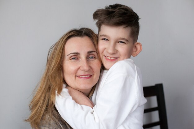 Heureuse mère et enfant mignon à la maison. portret de maman souriante étreignant son fils. Concept de maternité heureuse