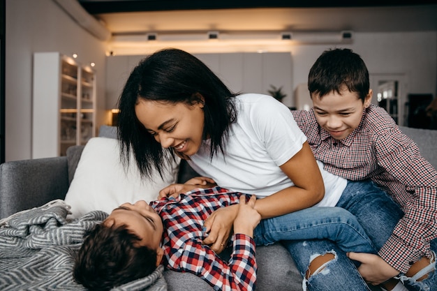 Heureuse mère de famille afro-américaine et ses deux fils s'amusant et s'amusant à la maison ensemble. Photo de haute qualité