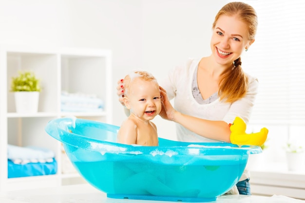 Photo heureuse mère de famille baigne le bébé dans un bain bleu