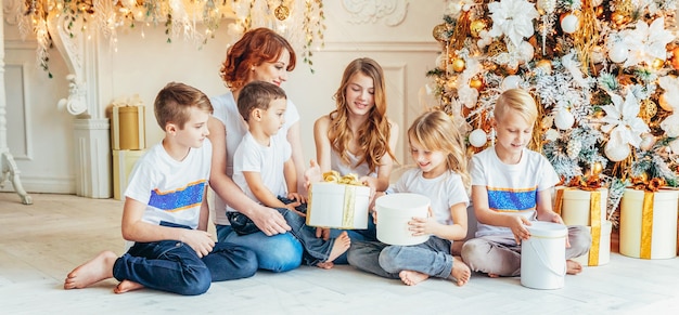 Heureuse mère de famille et cinq enfants se détendre en jouant près de l'arbre de Noël à la maison