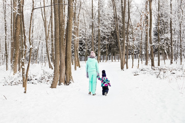 Heureuse mère de famille et enfant bébé fille sur une promenade d'hiver dans les bois