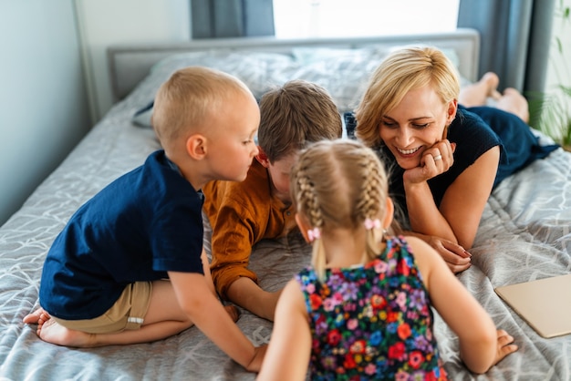 Heureuse mère de famille et enfants jouant avec des appareils numériques à la maison. Technologie, concept d'enfants.