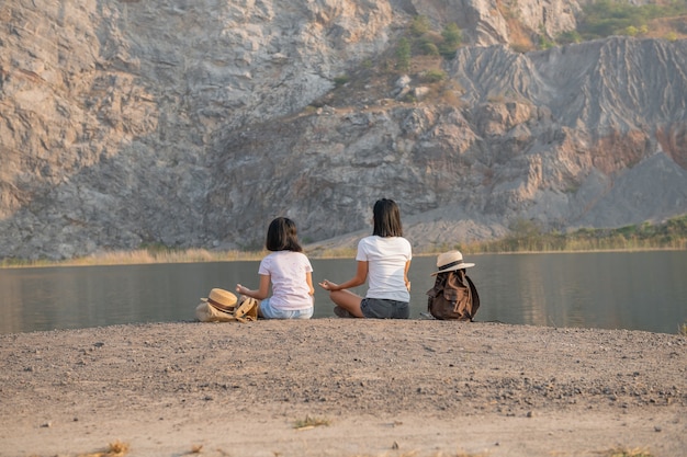 Heureuse mère de famille et fille enfant faisant de la méditation à l'extérieur près du lac