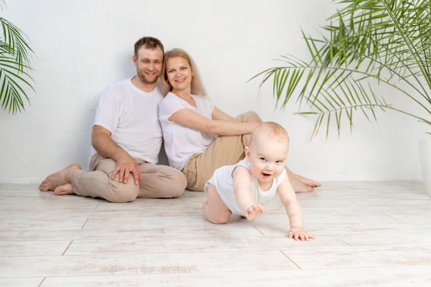 Heureuse mère de famille père et bébé à la maison s'amusant, bébé rampant au premier plan