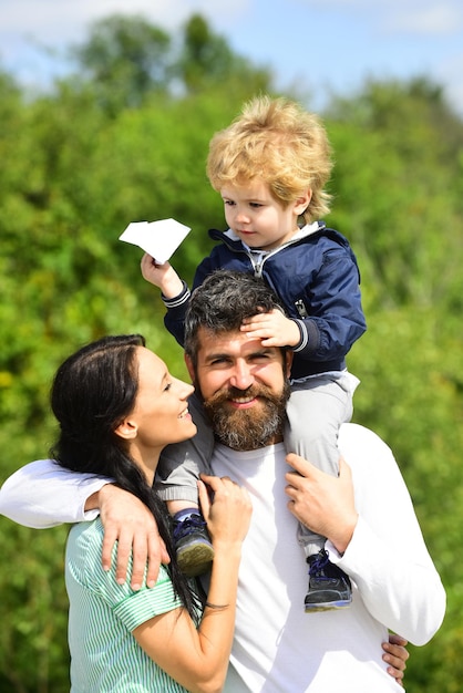 Heureuse mère de famille père et fils sur fond de ciel en été enfant heureux jouant avec du papier jouet p...