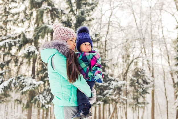 Heureuse mère de famille et petite fille jouant et riant en hiver à l'extérieur dans la neige.