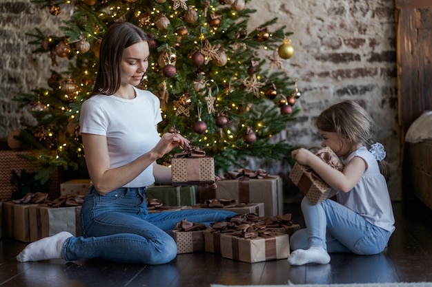 Heureuse mère de famille et sa fille donnant un cadeau de Noël et embrassant