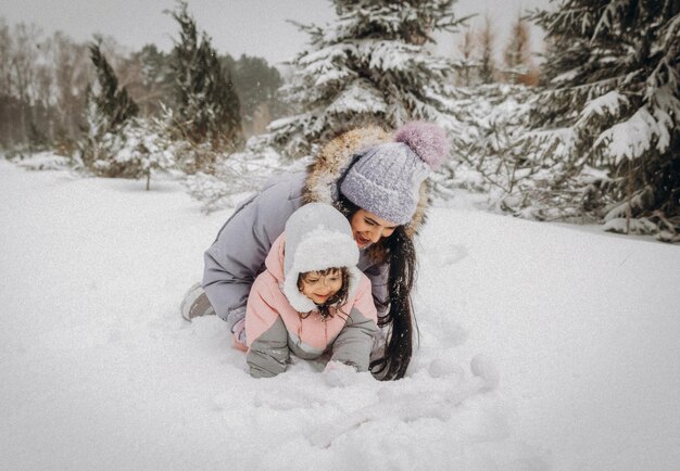 Heureuse mère de famille et sa fille s'amusent à jouer sur la promenade d'hiver à l'extérieur. famille dans la forêt d'hiver