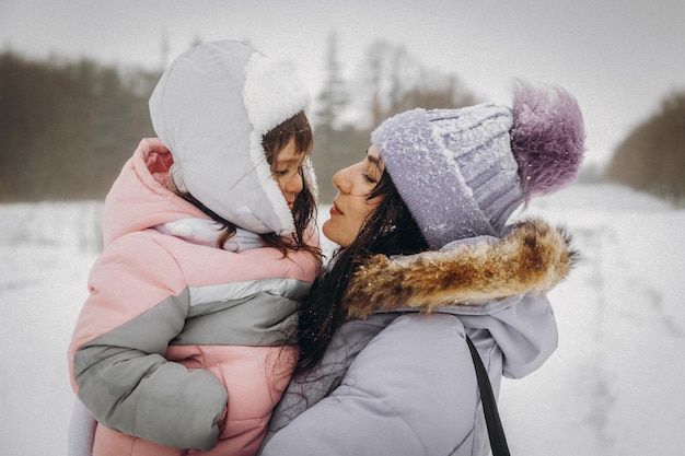 Heureuse mère de famille et sa fille s'amusent à jouer sur la promenade d'hiver à l'extérieur. portrait d'hiver de la mère et de l'enfant.