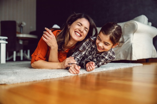 Heureuse mère et fille allongée sur le sol à la maison et en riant.