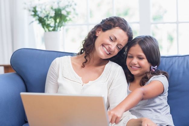 Heureuse Mère Et Fille Assise Sur Le Canapé Et Utilisant Un Ordinateur Portable