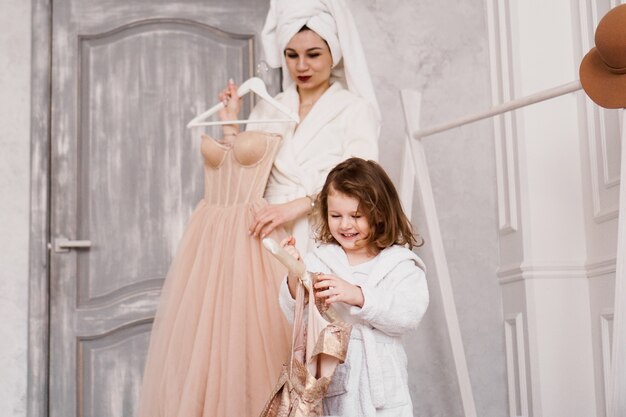 Heureuse mère et fille choisissent une robe dans la garde-robe. La mère porte un peignoir blanc. Ils vont à la fête.