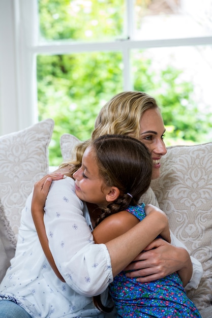 Heureuse mère et fille embrassant sur le canapé