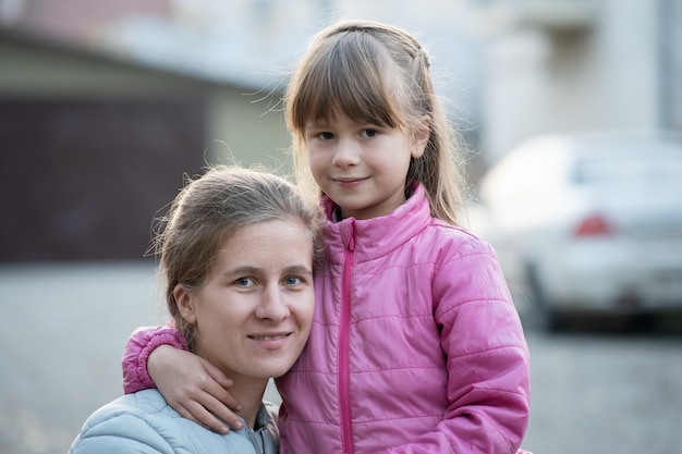 Heureuse mère et fille enfant étreignant ensemble à l'extérieur.