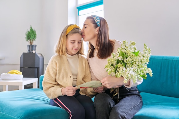 Heureuse mère et fille enfant félicitant avec bouquet de fleurs et carte