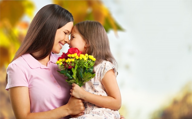 Heureuse mère et fille étreignant avec des fleurs