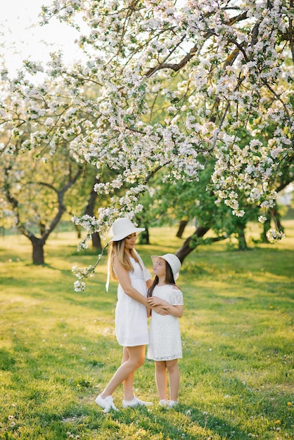 Heureuse mère et fille de famille dans un verger de pommiers en fleurs au printemps