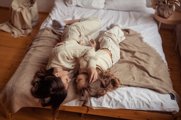 Heureuse mère et fille de famille s'amusent à la maison sur le lit