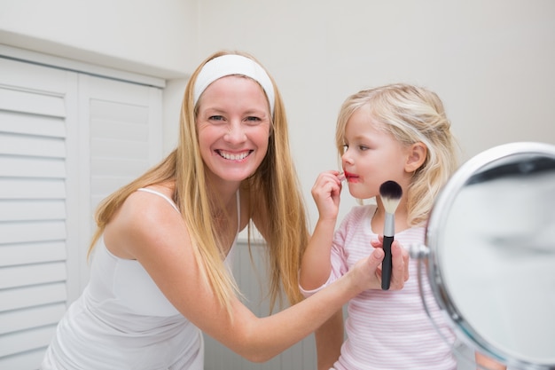 Heureuse mère et fille jouant avec maquillage