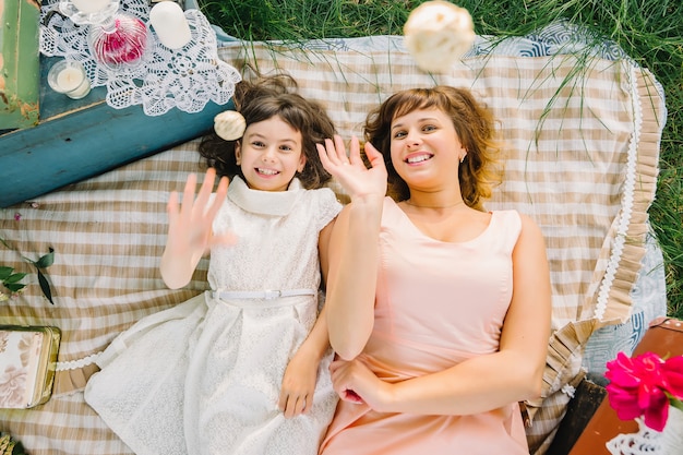 Heureuse mère et fille jouant et souriant en position couchée sur une couverture en été