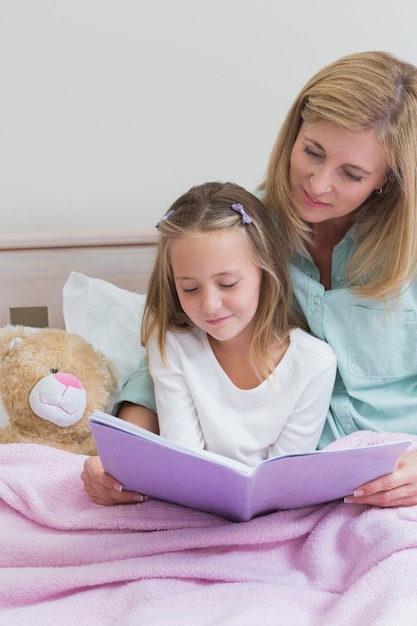 Heureuse mère et fille lisant un livre