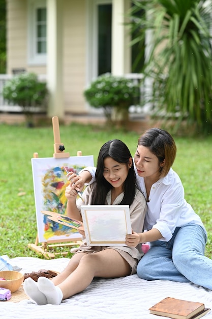 Heureuse mère et fille peignant à l'aquarelle ensemble dans le jardin