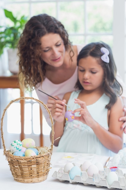 Heureuse mère et fille peignant des oeufs de Pâques