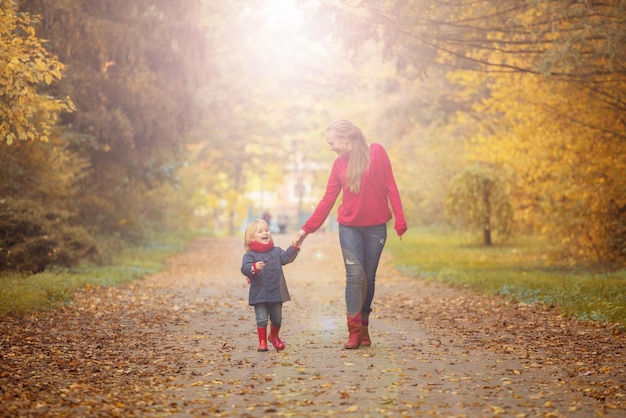 Heureuse mère et fille se promènent dans un parc en automne