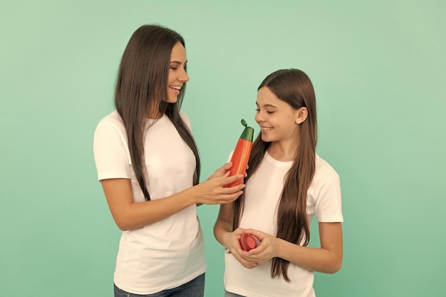 Heureuse mère et fille sentent la bouteille de shampoing sur fond bleu