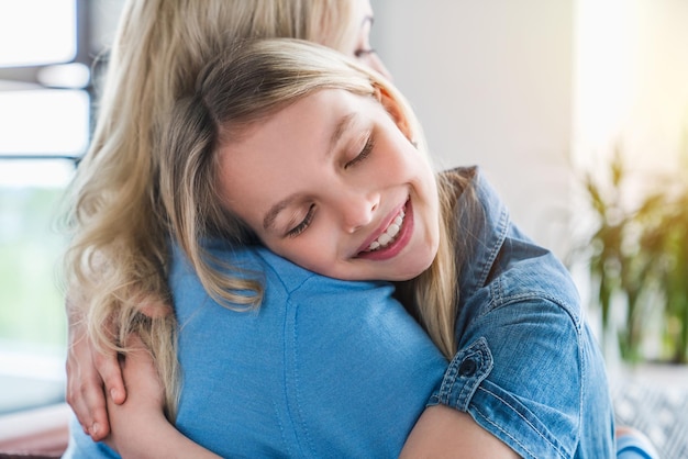 Heureuse mère et fille serrant les yeux fermés à l'intérieur de la maison