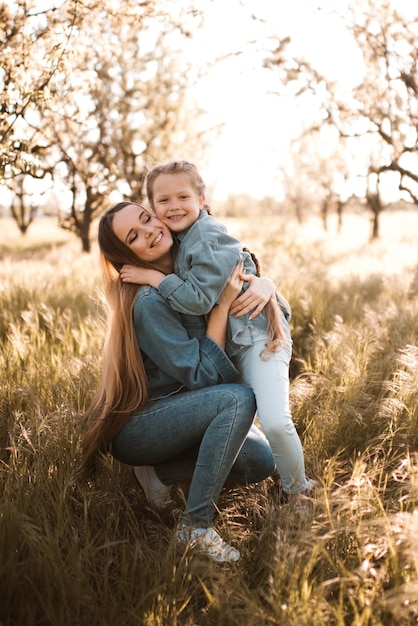 Heureuse mère avec une fille souriante portant des vêtements en denim dans un pré ensemble