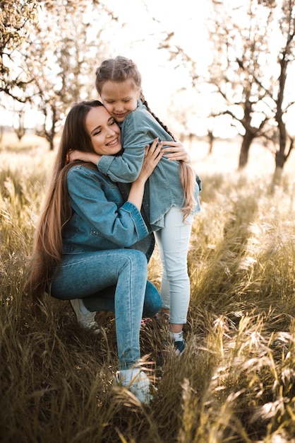 Heureuse mère avec une fille souriante portant des vêtements en denim dans un pré ensemble