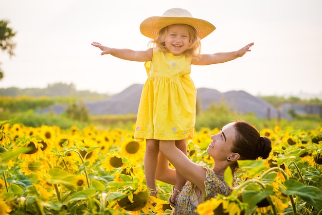 Heureuse mère avec la fille sur le terrain avec des tournesols