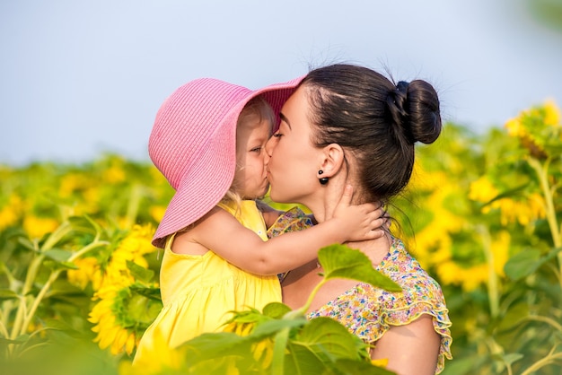 Heureuse mère avec la fille sur le terrain avec des tournesols