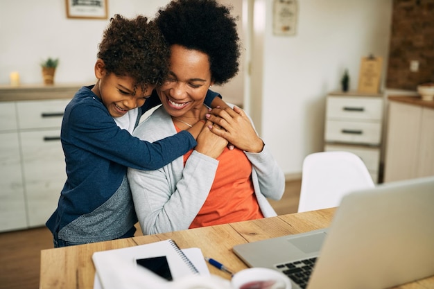 Heureuse mère et fils afro-américains embrassant à la maison