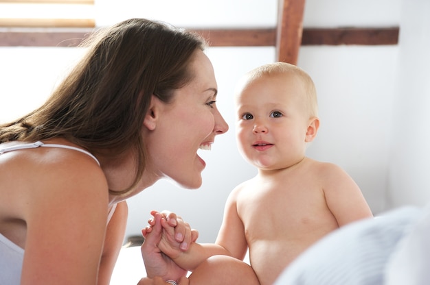 Heureuse mère jouant avec bébé au lit