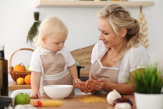 Heureuse mère et petite fille cuisinant dans la cuisine. Passer du temps tous ensemble, concept de plaisir en famille.