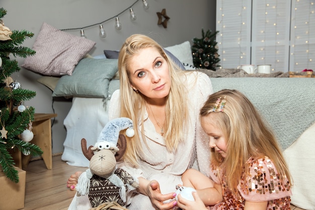 Heureuse mère et petite fille décorant le sapin de Noël à la maison, vacances, célébration, concept de famille et de personnes