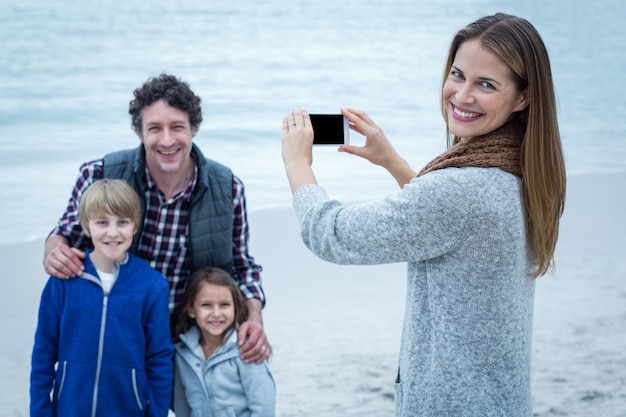 Heureuse mère photographiant la famille à la plage