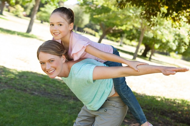 Heureuse mère portant la fille au parc