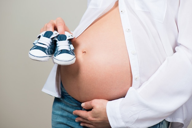 Heureuse mère en prévision de la naissance de son fils Femme enceinte tenant des chaussons pour bébé