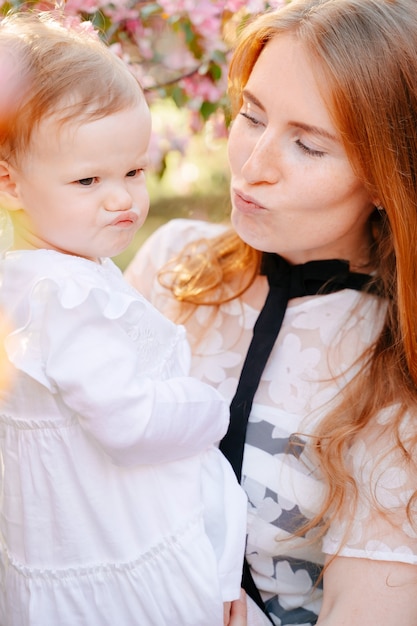 Heureuse mère rousse avec une petite fille dans ses bras s'amuser et faire des grimaces paresse et mars des mères