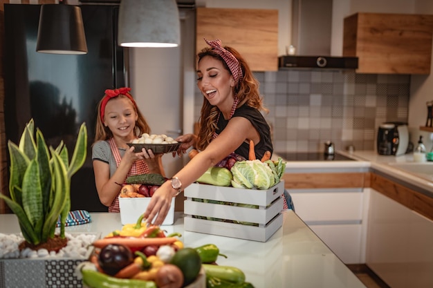 Heureuse mère et sa fille aiment préparer et manger des repas sains ensemble dans leur cuisine à domicile.