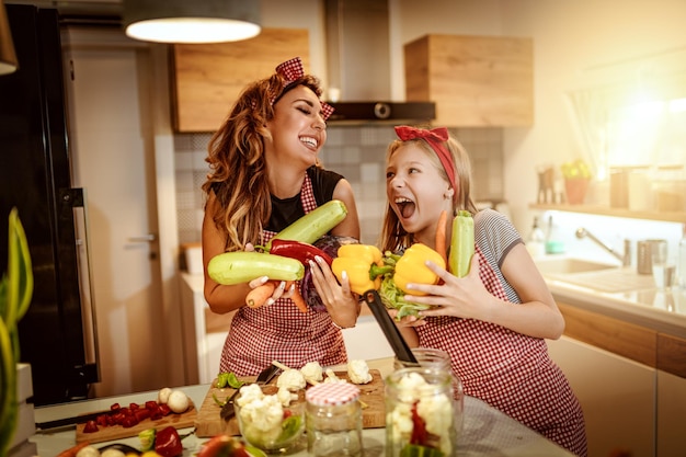 Heureuse mère et sa fille aiment se préparer à faire mariner des légumes et à préparer des repas sains ensemble dans leur cuisine à domicile.