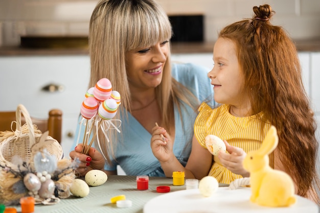 Heureuse mère et sa fille bien-aimée peignent des oeufs de Pâques
