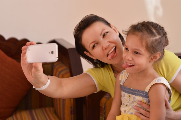 Heureuse mère avec sa fille dans un parc d'été avec téléphone