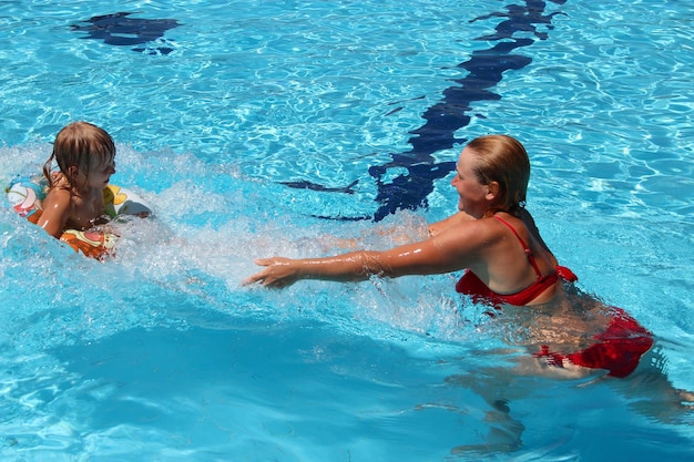 Heureuse mère avec sa fille profite de vacances dans la piscine Famille heureuse Famille profitant des vacances d'été Personnes profitant des vacances en famille Équipe féminine