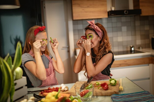 Heureuse mère et sa fille s'amusent et s'amusent à préparer et à prendre des repas sains ensemble dans leur cuisine à domicile.