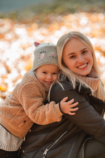 Heureuse mère et sa fille se promènent dans le parc d'automne Belle famille dans des vêtements chauds Automne