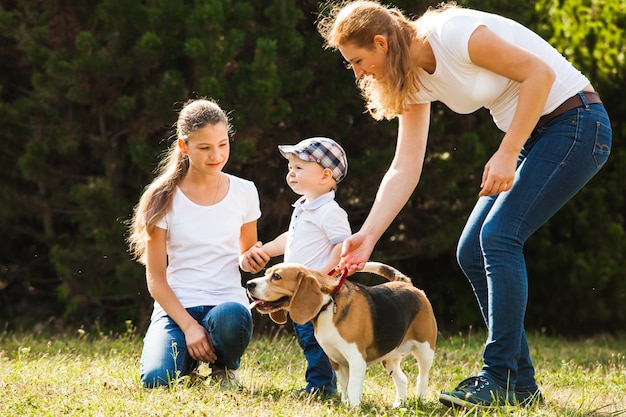 Heureuse mère avec sa fille, son petit fils et son chien beagle pour une promenade